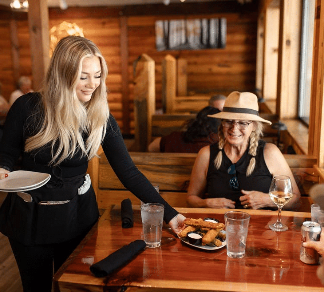 A waitress serving a lady in a restaurant with a warm ambience