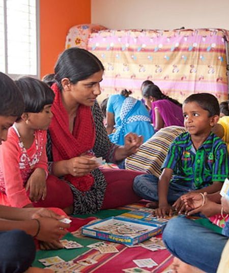 People and children, sitting on mats, working on projects, indoor setting - Shreyas Retreat