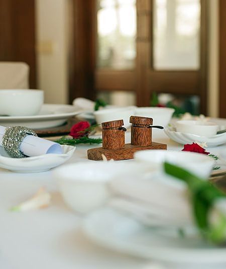 A table set with plates and cutlery, surrounded by windows - Shreyas Retreat