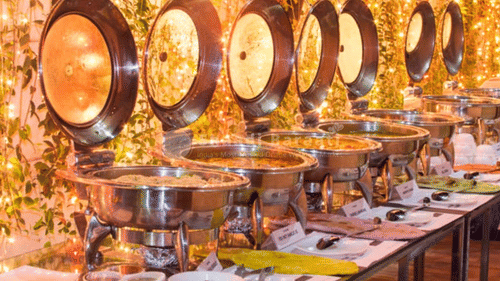 Buffet counter at Uday Palace Convention Centre featuring containers filled with dishes with ladles placed on plates