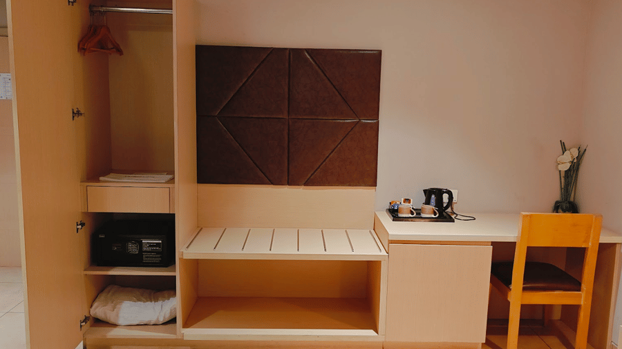 Deluxe Double Room with a dedicated seating area, wooden furniture, and warm lighting at Cholaa Dynasty, Kumbakonam offering a spacious and functional layout perfect for relaxation during your stay in Kumbakonam