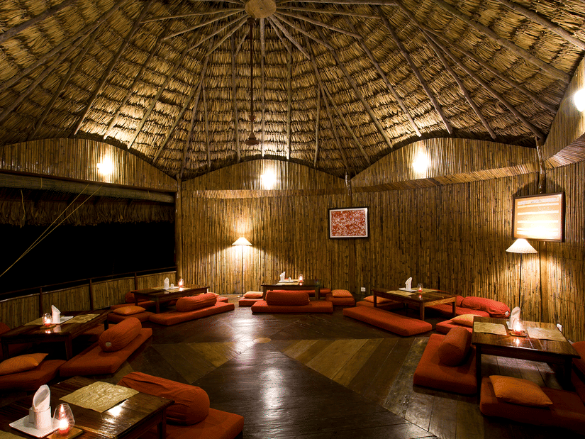 Wamly lit The Common Elephant featuring tables and plush seaters on the floor at Barefoot at Havelock, one of the beach resorts in Havelock, Andaman