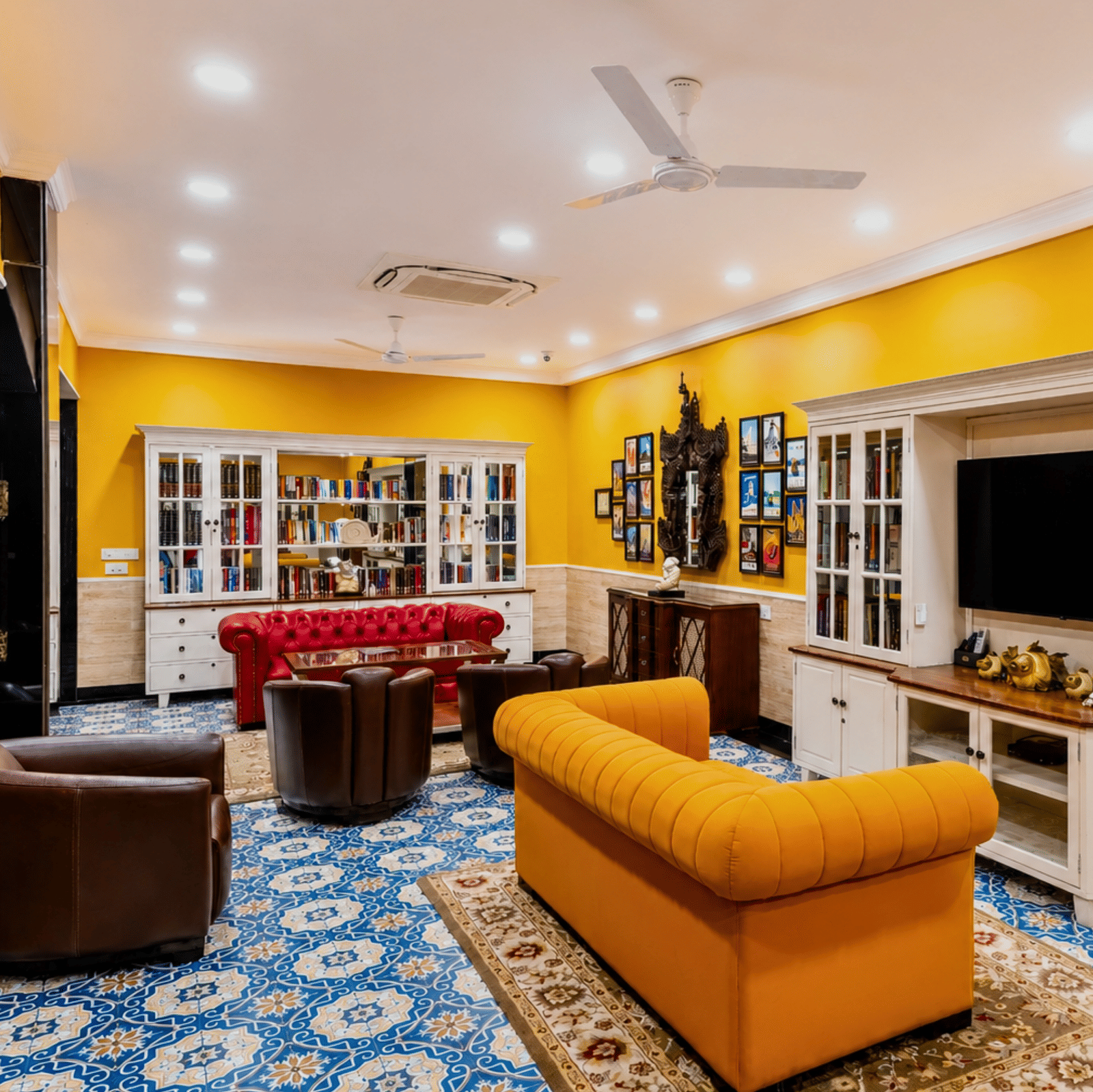 Library lounge with glass-fronted bookcases, sofas, leather armchairs and a patterned tiled floor at MAYFAIR Palm Beach Resort, Gopalpur-on-Sea.