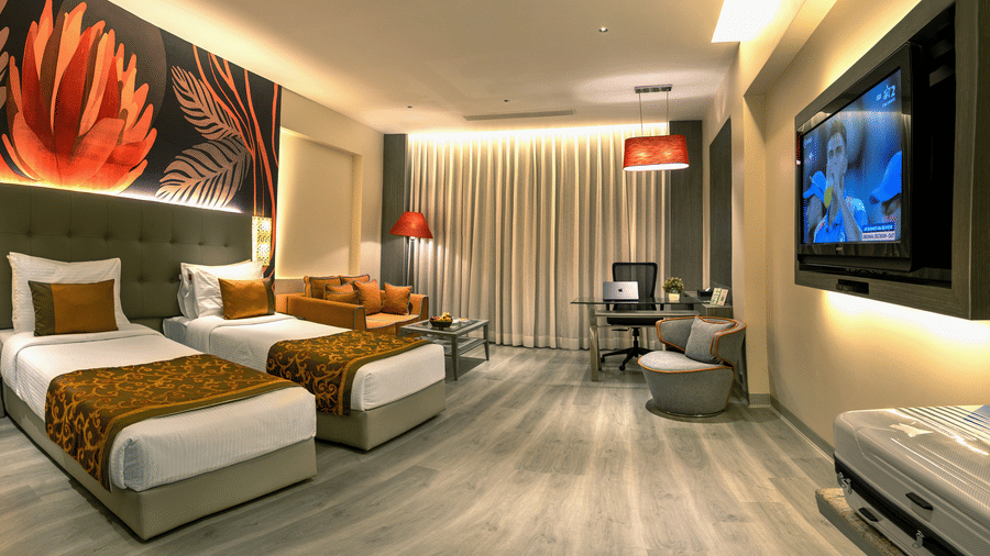Executive Room at The Sonnet, Kolkata with twin beds, a patterned feature wall, bedside tables and a wall mounted television.