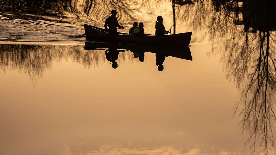 a family of four travelling in a boat with the water reflecting the sky