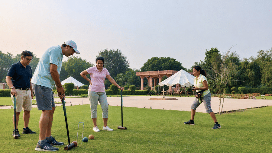 Guests playing a game of croquet on the expansive green lawn at The Umaid Palace with garden pavilions in the background.