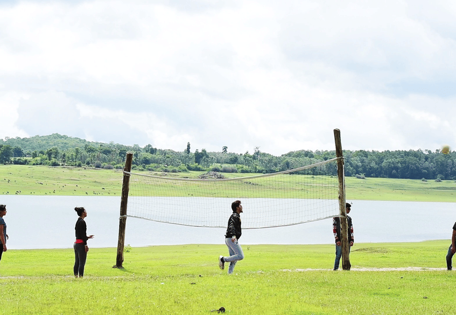 Image of a group of people playing volleyball beside a water body at Coorg Jungle Camp Backwater Resort, Kushalnagar.