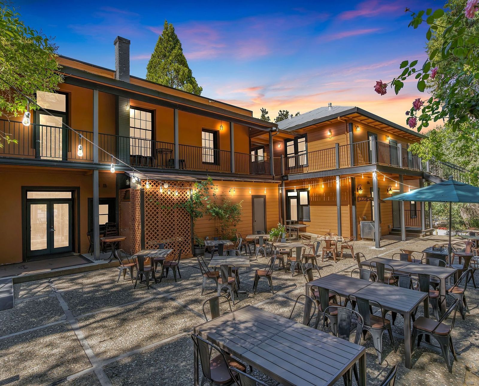 A view of the exterior of The Groveland Hotel with tables and chairs arranged in the backyard