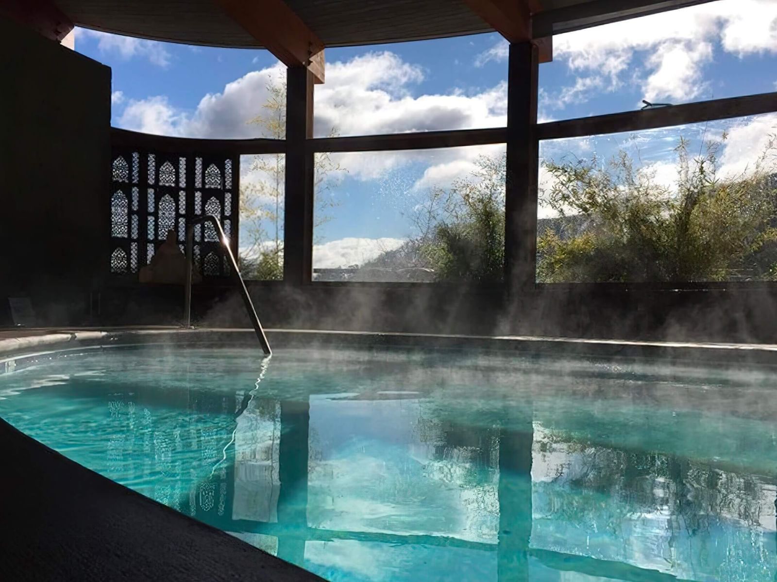 The Tallman Hotel's inviting indoor pool with steam rising and large windows offering scenic views.
