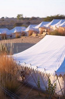 An image of the tent area at MANVAR Resort & Desert Camp in the desert with sparse greenery