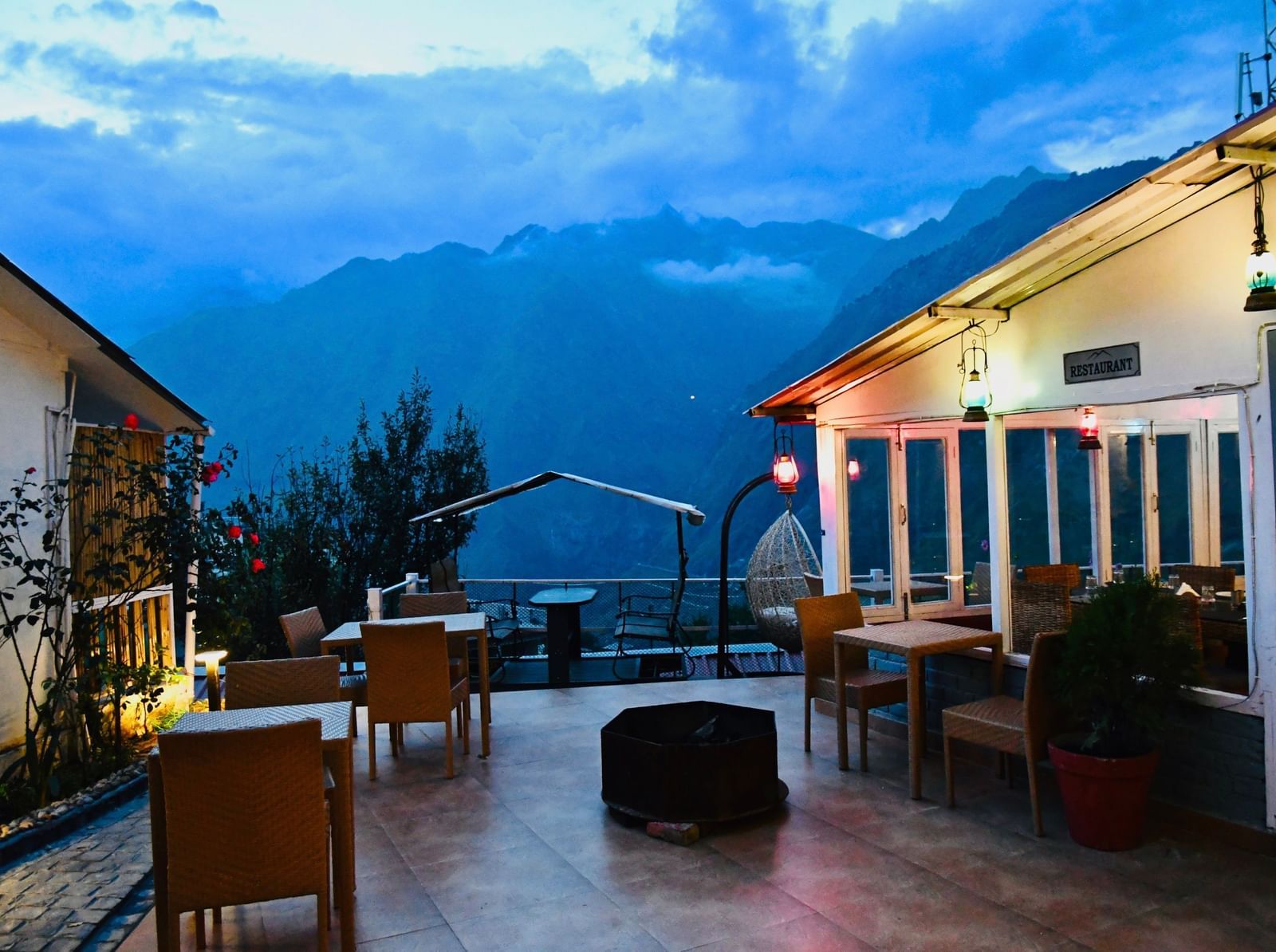 image of the outdoor seating area at the tattva, joshimath with beautiful mountain landscapes in the background on a late evening