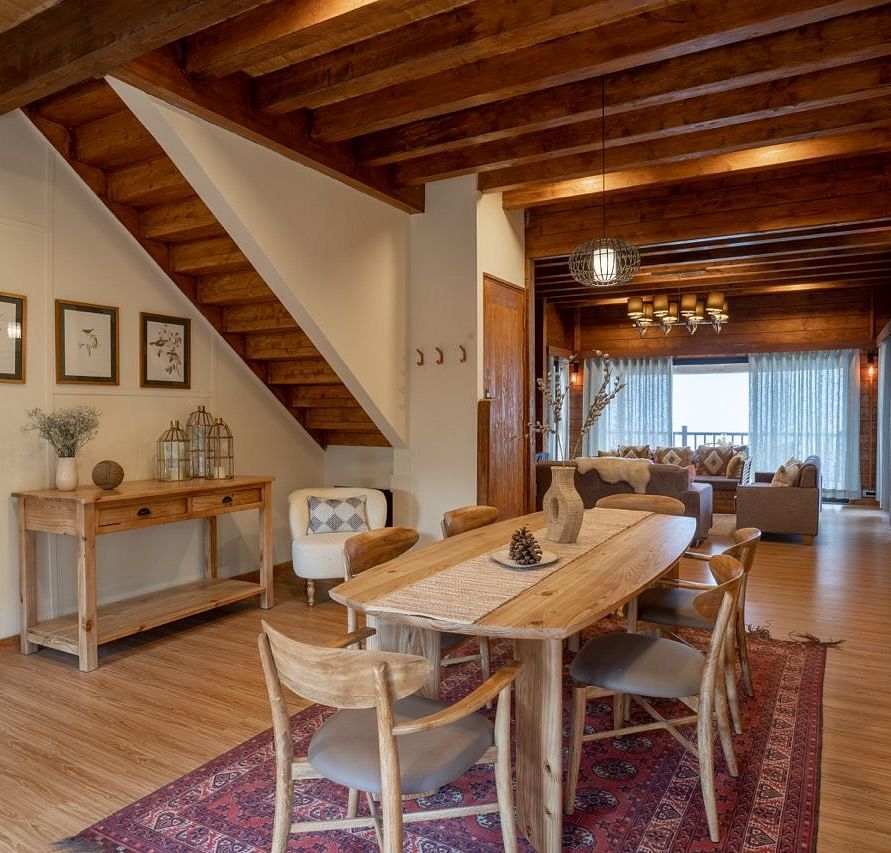 An image of dining space with table and chairs and stairs leading to the attic - Avalon Cottages, Kanatal