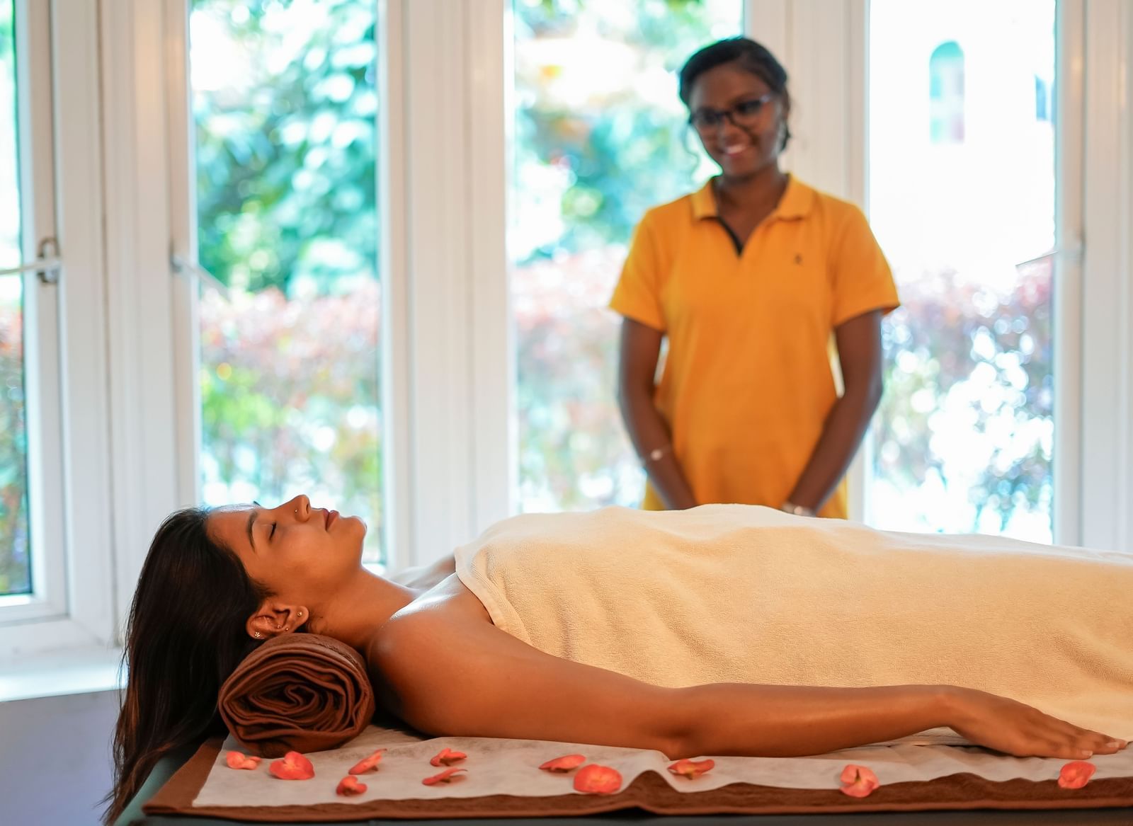 A lady lying on a spa bed and a therapist standing beside her at WOW Bungalow, Yercaud.