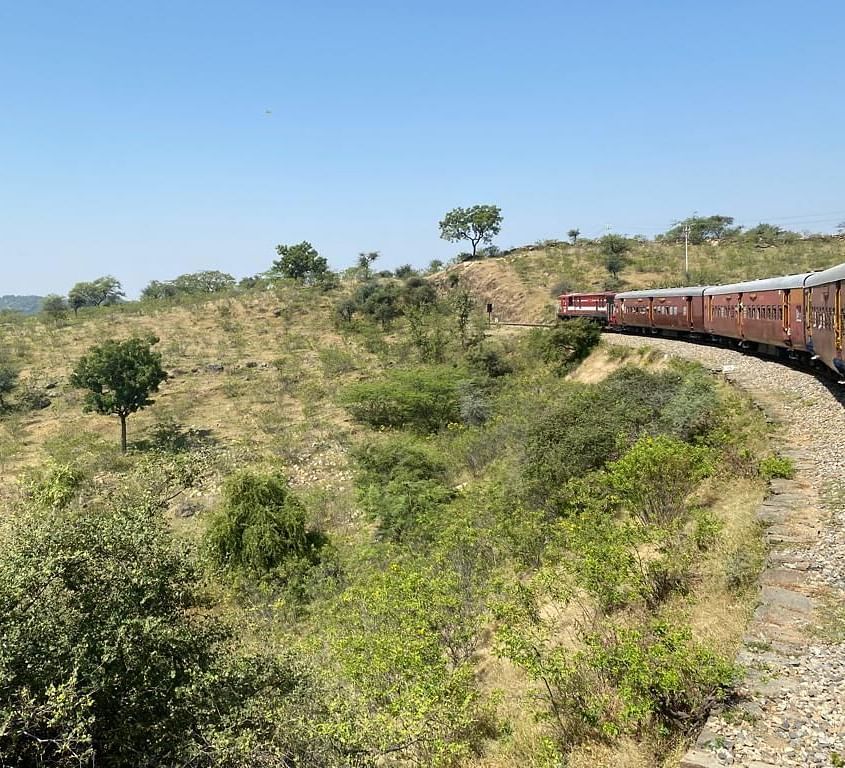 A train travelling through a grassland on a clear blue day