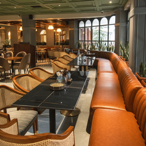 An image of a restaurant featuring a bunch of well-decorated tables, chairs, and sofas in daytime - Hotel Polo Towers, Shillong 