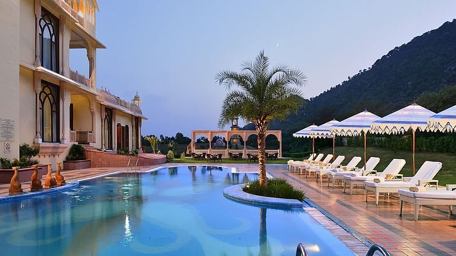 Image of the pool at Rajasthali Resort & Spa Jaipur with lounge chairs on the side.