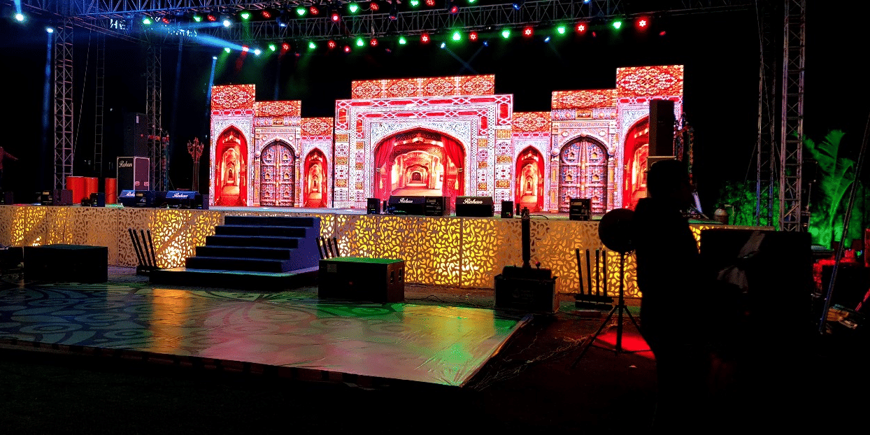 A decorated platform with a staircase, glowing lights, and a monument-like installation at Gulmohar garden of Papaya Tree Hotels.