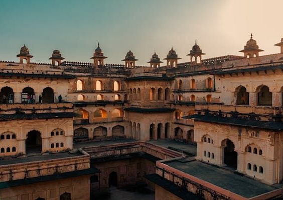 An expansive palace courtyard with multiple levels and arched openings, under a soft twilight sky.
