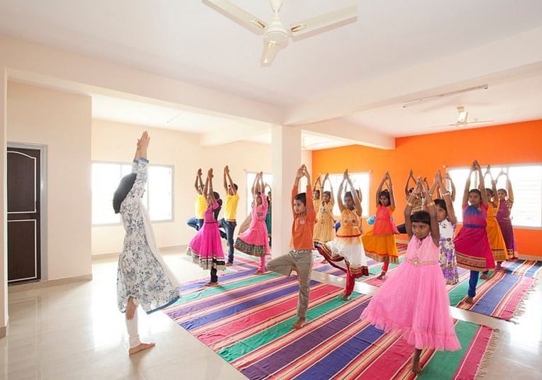 People performing yoga in colorful costumes, indoor setting - Shreyas Retreat