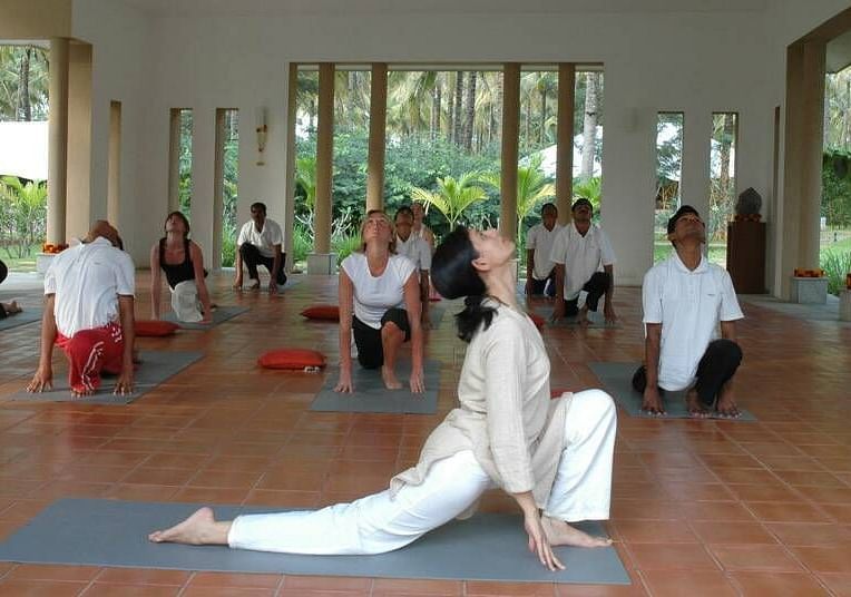 People doing yoga poses on mats, indoor setting, group exercise - Shreyas Retreat