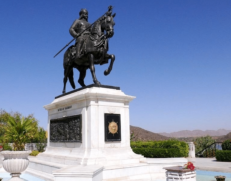 A statue of a man on a horse stands on a pedestal against a clear sky.