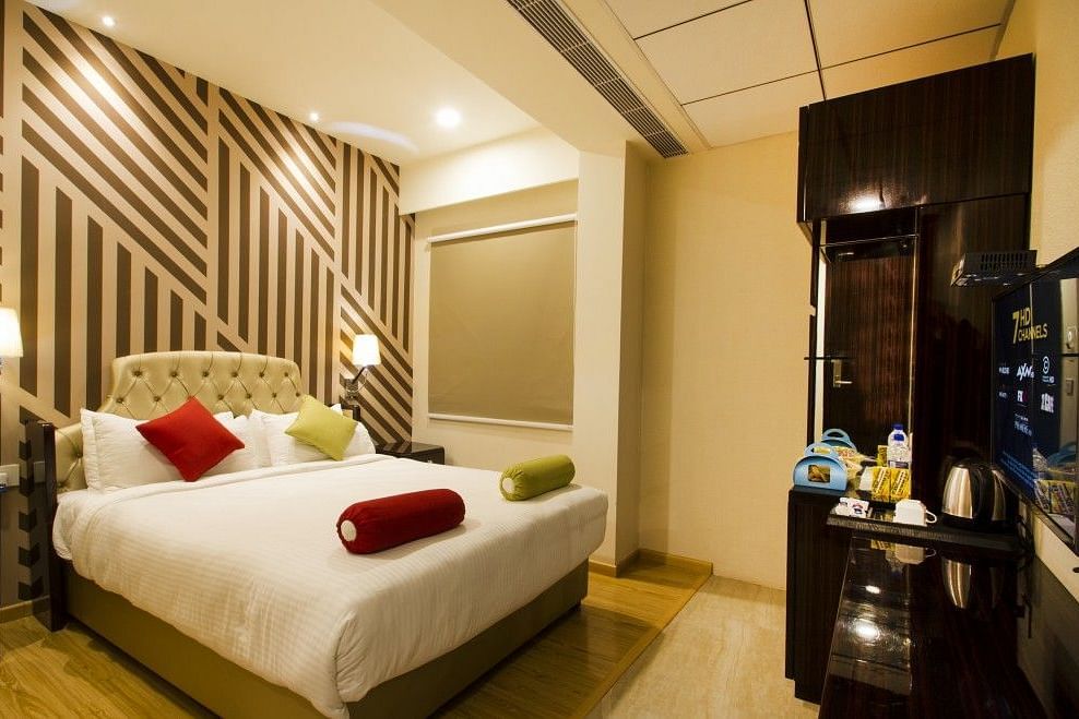 Standard room with bed, television and dressing table at Art Boutique Hotel, Hyderabad