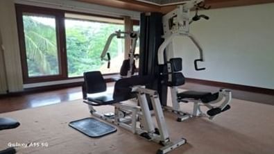 An empty home gym with a multi-station exercise machine and a large window overlooking trees