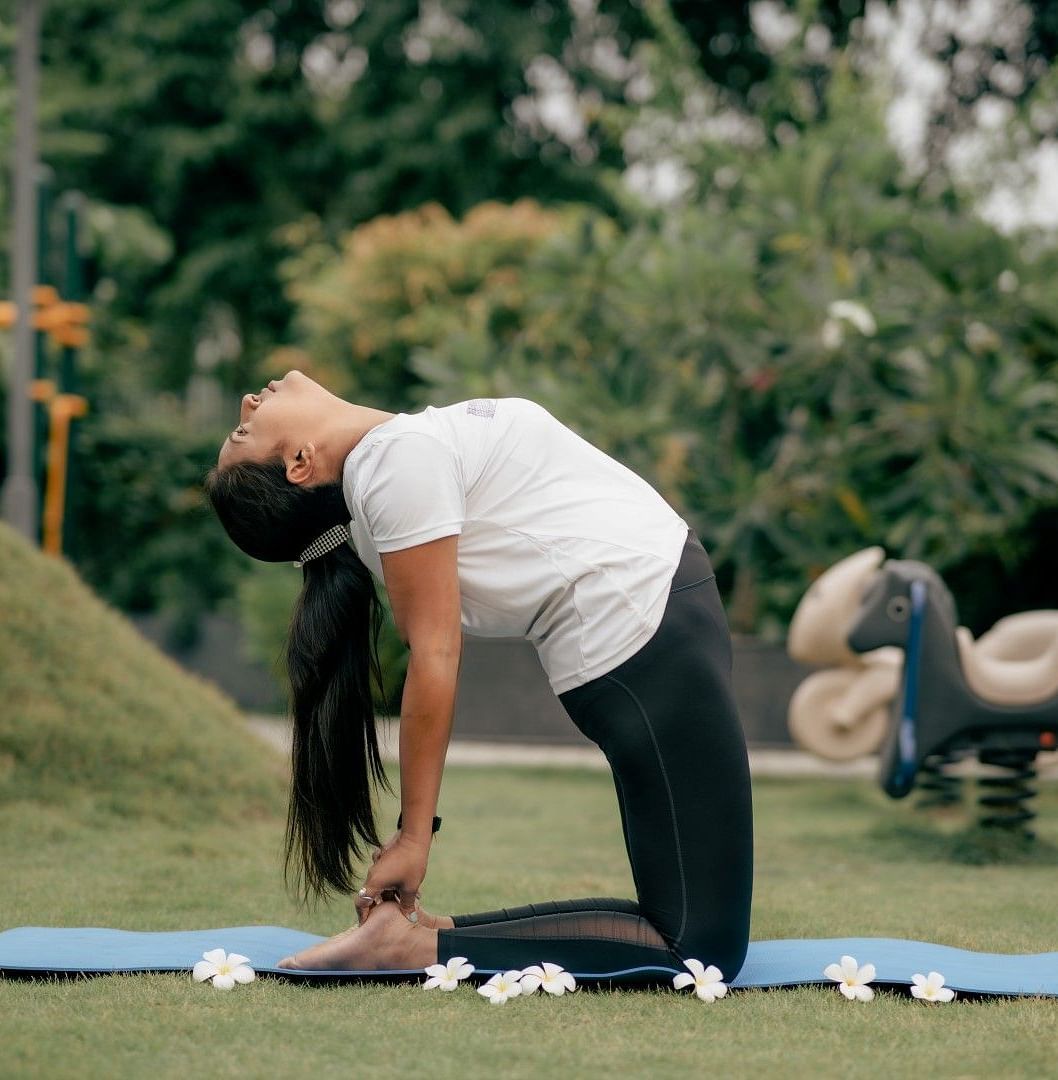 A lady doing yoga in a park during the day