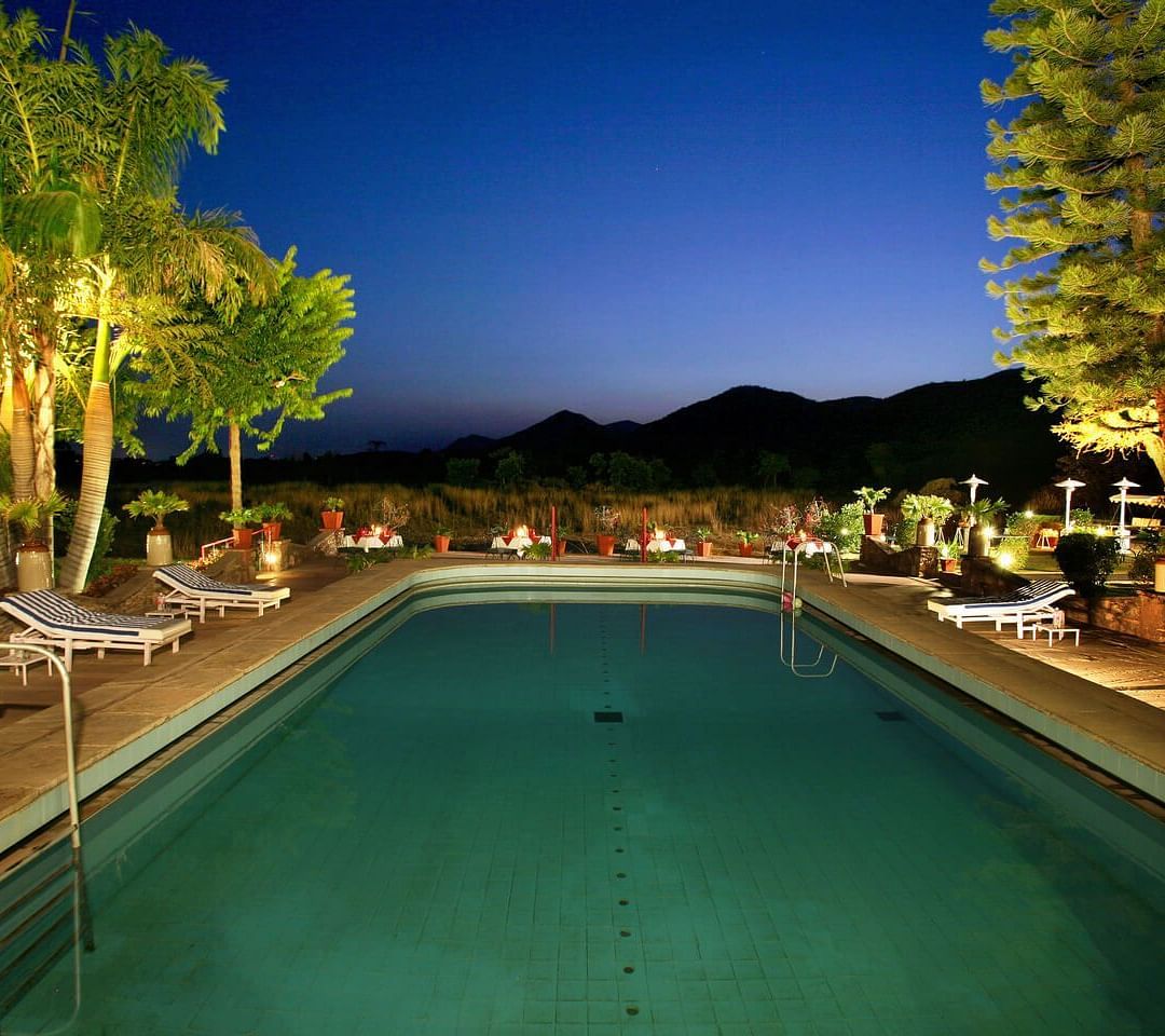 A swimming pool at Shikarbadi Hotel illuminated with lights