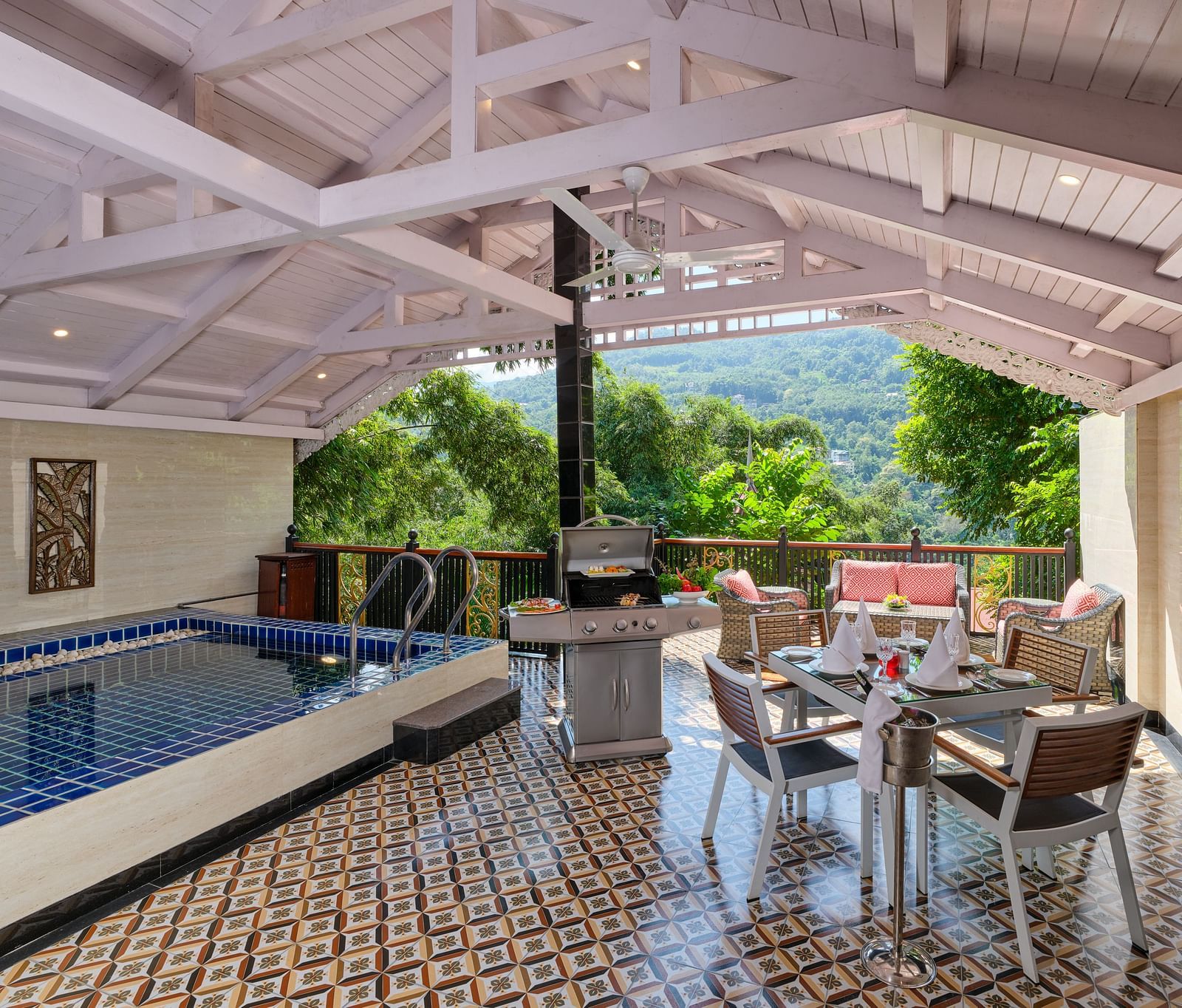 Swimming pool in Imperial Villa with a sating area and barbecue grill with a wooden ceiling and a balcony overlooking greenery.
