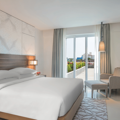 King Room with a balcony decked with a plush bed, couch and television at The Residency Towers Rameswaram