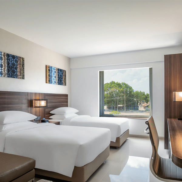 Standard twin room decked with two beds, television and a working desk at The Residency Towers Rameswaram