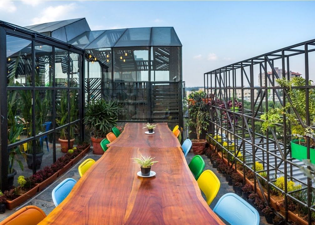 a long wooden dining table surrounded by bright colourful chairs.