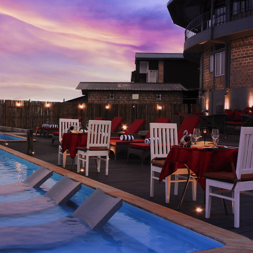 Dining tables and chairs set by the poolside at Polo Cherrapunjee Resort
