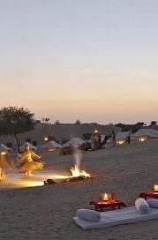 A luxury desert tent with an extended canopy stands amid a dry landscape with sparse trees, under a clear sky - MANVAR Resort & Desert Camp