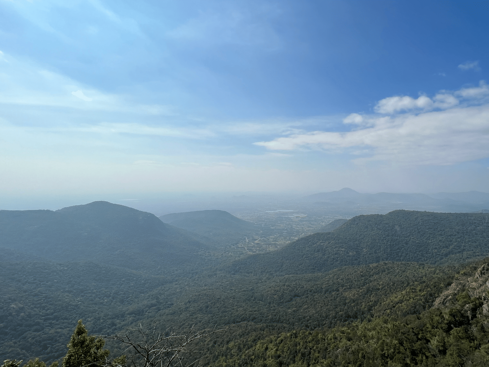 Panoramic view of a wide valley with distant mountains under a clear sky.
