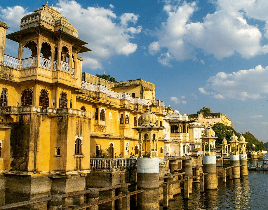 A building with ornate details lines a body of water under the sky with fluffy clouds.