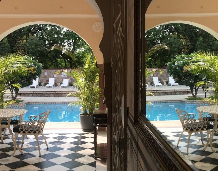 A beautiful poolside view framed by arched pillars and checkerboard flooring - Khas Bagh ,Jaipur.