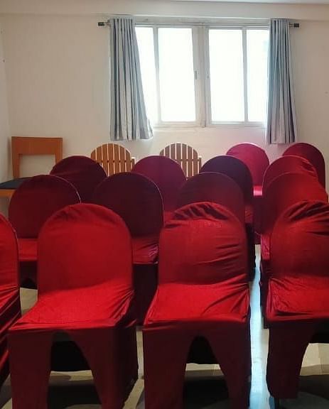 Spacious seminar hall at Lords Eco Inn Dahej featuring red fabric chairs arranged in rows with natural lighting from large windows