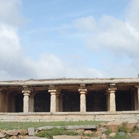 Ancient stone temple ruins under a cloudy sky, Hampi