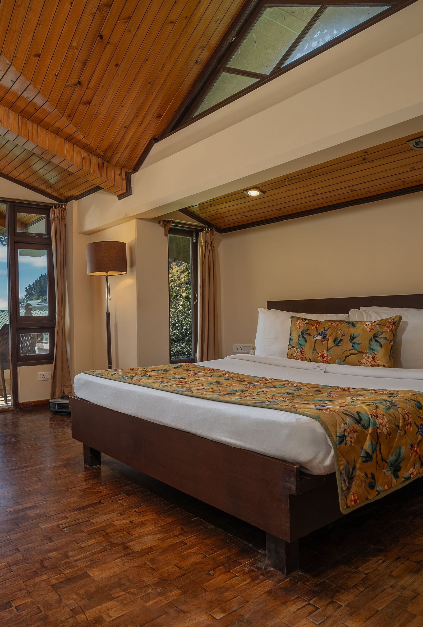 Deluxe room with a spacious bed, wooden furniture such as a bedside table, dining table, and chair at Summit Norling Resort & Spa, Gangtok