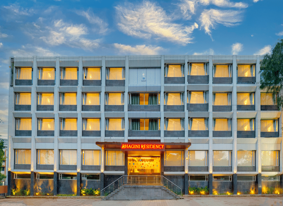 The illuminated exterior facade, lit windows, and entrance of Icon Express By Bhagini, Mahadevapura under an evening sky.