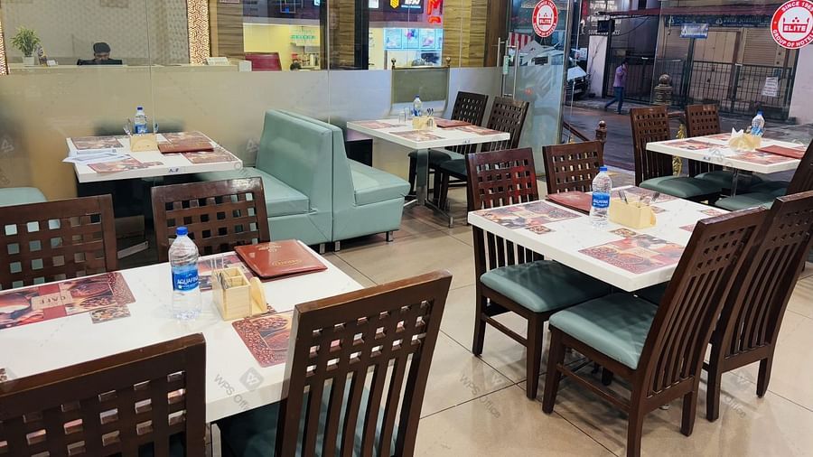 Casual dining area with neatly set water bottles, menu card, spoon stand on the table and modern decor at Hotel Dr Rajkumar International restaurant.