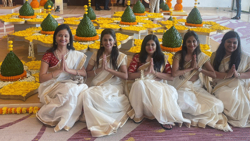 Bridesmaids dressed in white sarees sitting beside ceremonial decorations at Central Heritage Resort.