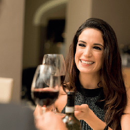 image of a woman toasting a wine glass at a dinner table setup
