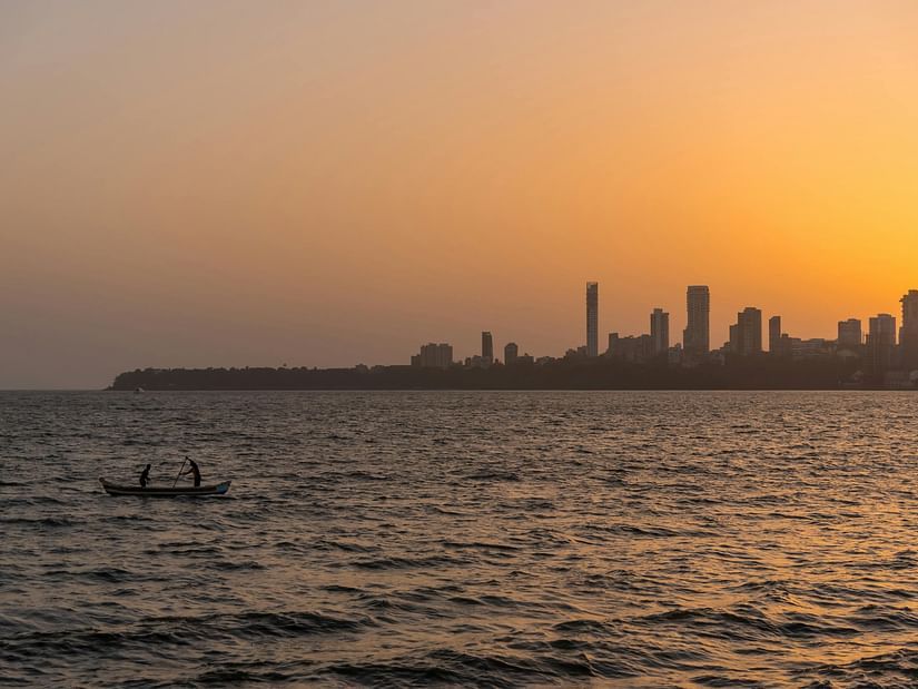 An image of a river where a boat is floating and buildings can be seen at the horizon