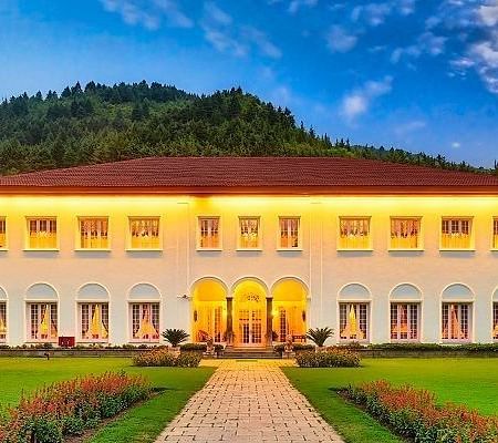 A front view of The Lalit Grand Palace Srinagar with a green lawn in front
