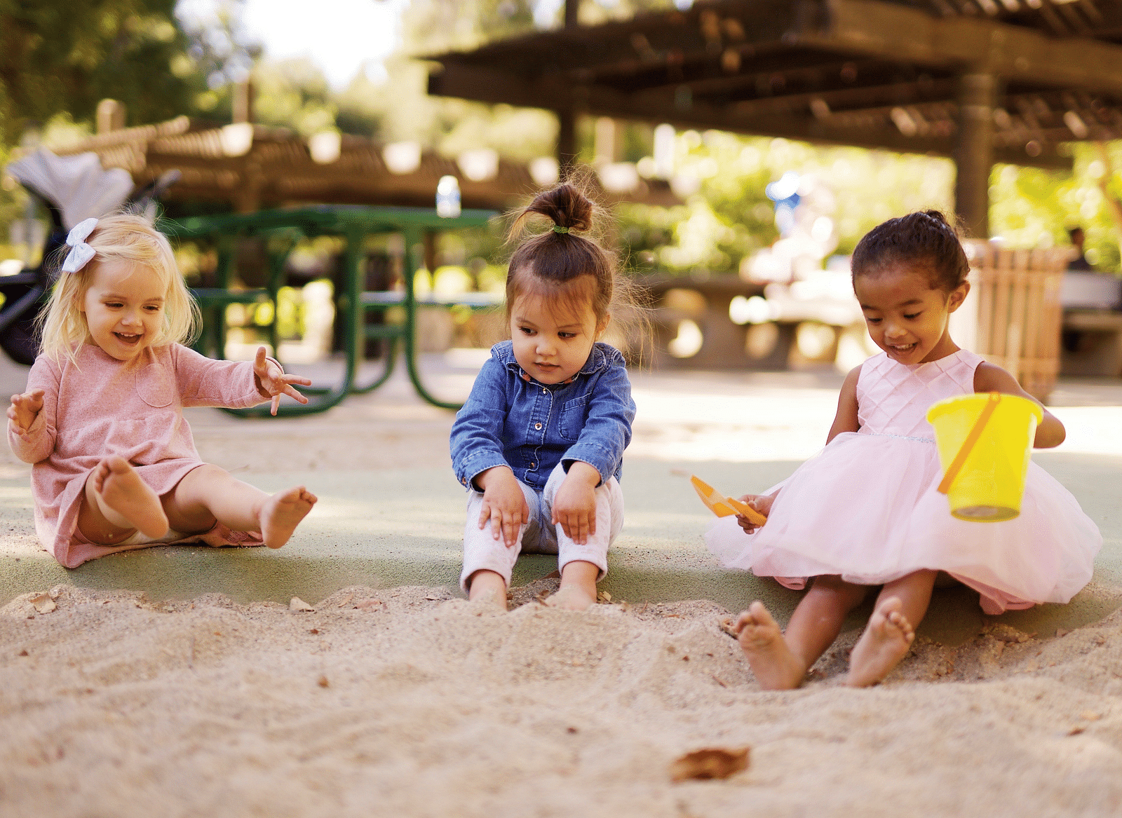 Three young children sitting on the ground and playing.