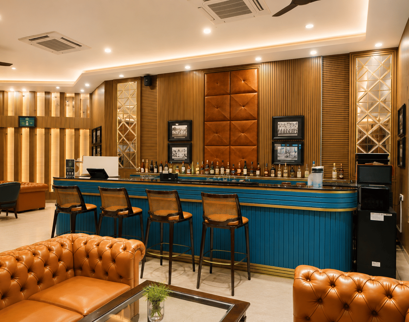 Off Side Bar with a teal counter, cane bar stools, leather sofas, spirit bottles and framed black-and-white photographs at MAYFAIR World Cup Village, Rourkela.