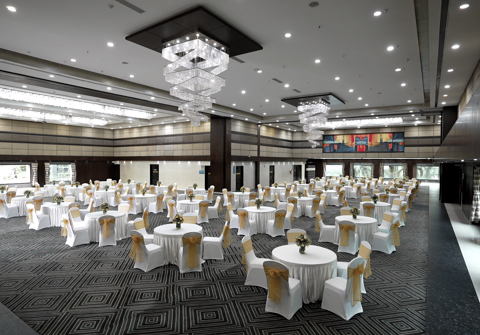 Spacious banquet hall with round tables and a chandelier ceiling - Narayani Heights Hotel & Resorts